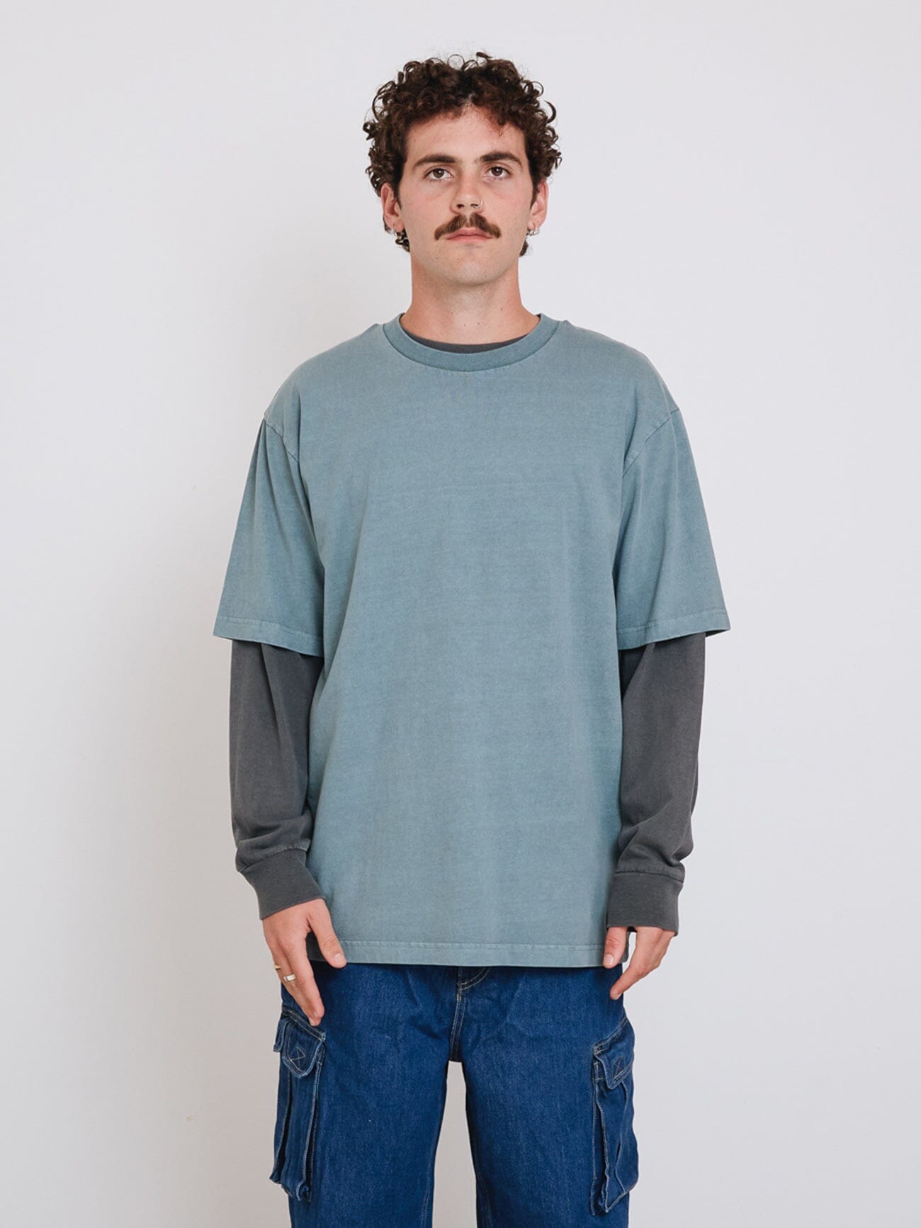 Male model wearing our Thrills Thrills Military Oversize Fit Tee in Blue standing against a plain studio background.