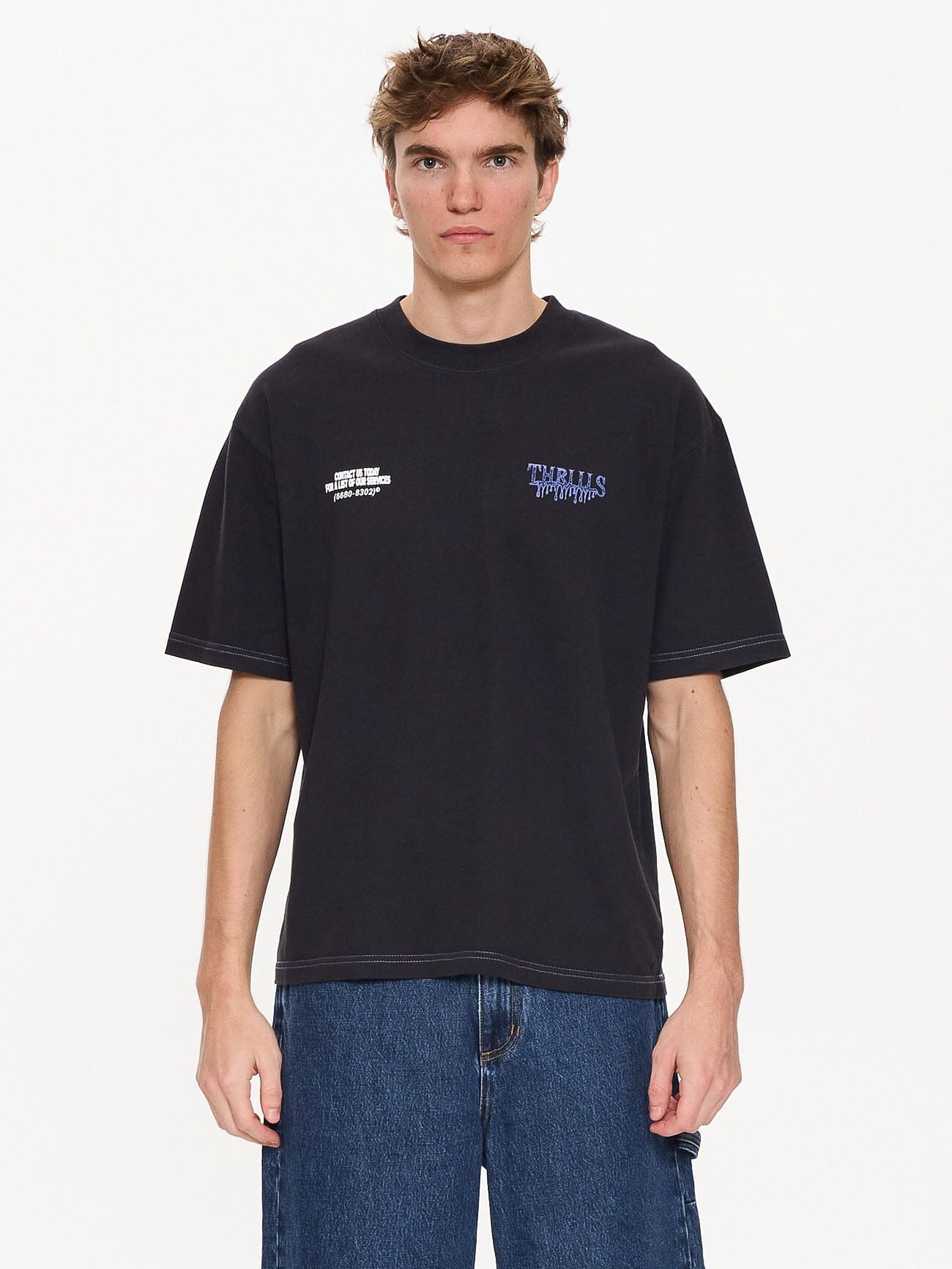 Male model wearing our Thrills Dispatch Box Fit Oversize Short Tee in Blue standing against a plain studio background.
