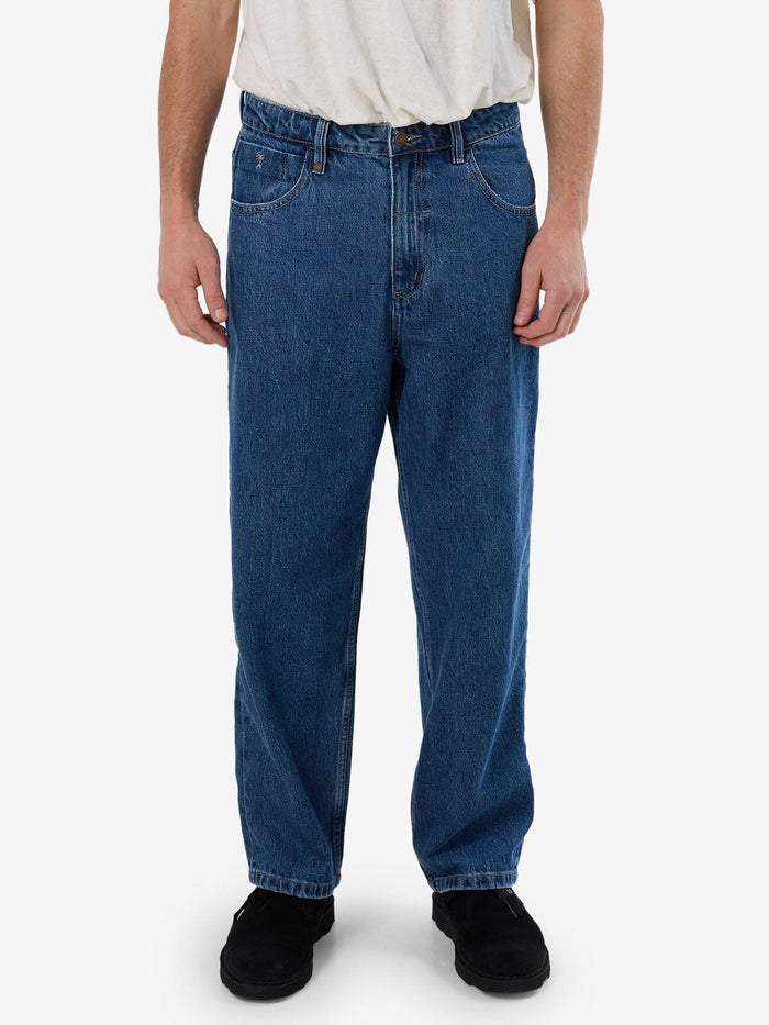 Male model wearing our Thrills Big Slacker Denim Jean in Blue standing against a plain studio background.