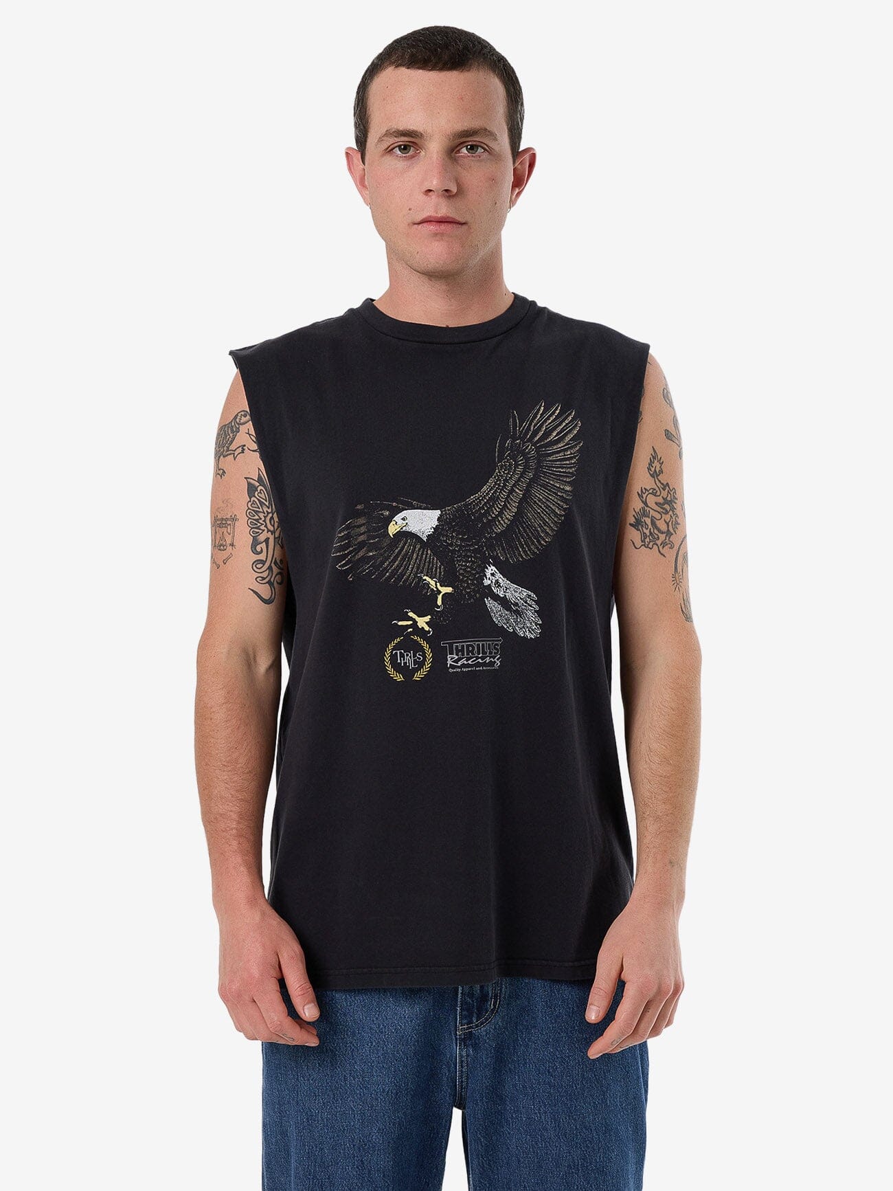 Male model wearing our Thrills Speed Tour Merch Fit Muscle Tee in Black standing against a plain studio background.