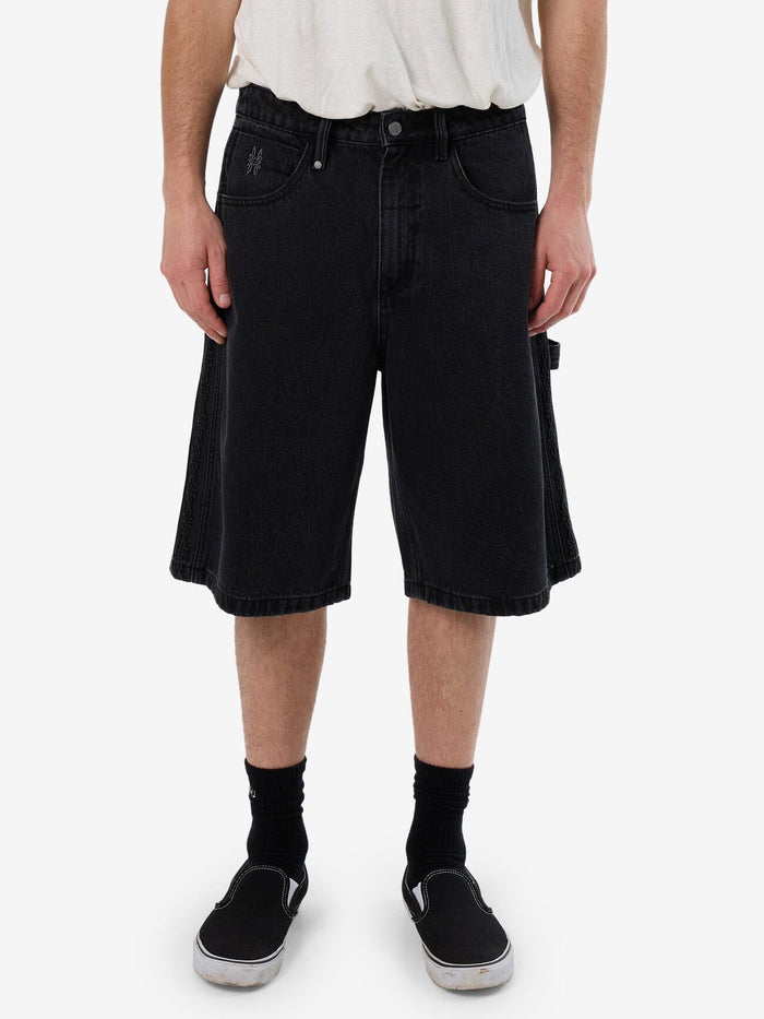 Male model wearing our Thrills Lighten Up Big Slacker Denim Short in Black standing against a plain studio background.