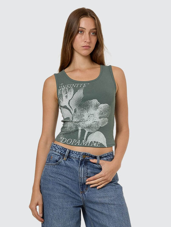 Woman wearing a green tank top with floral design and blue jeans on a white background