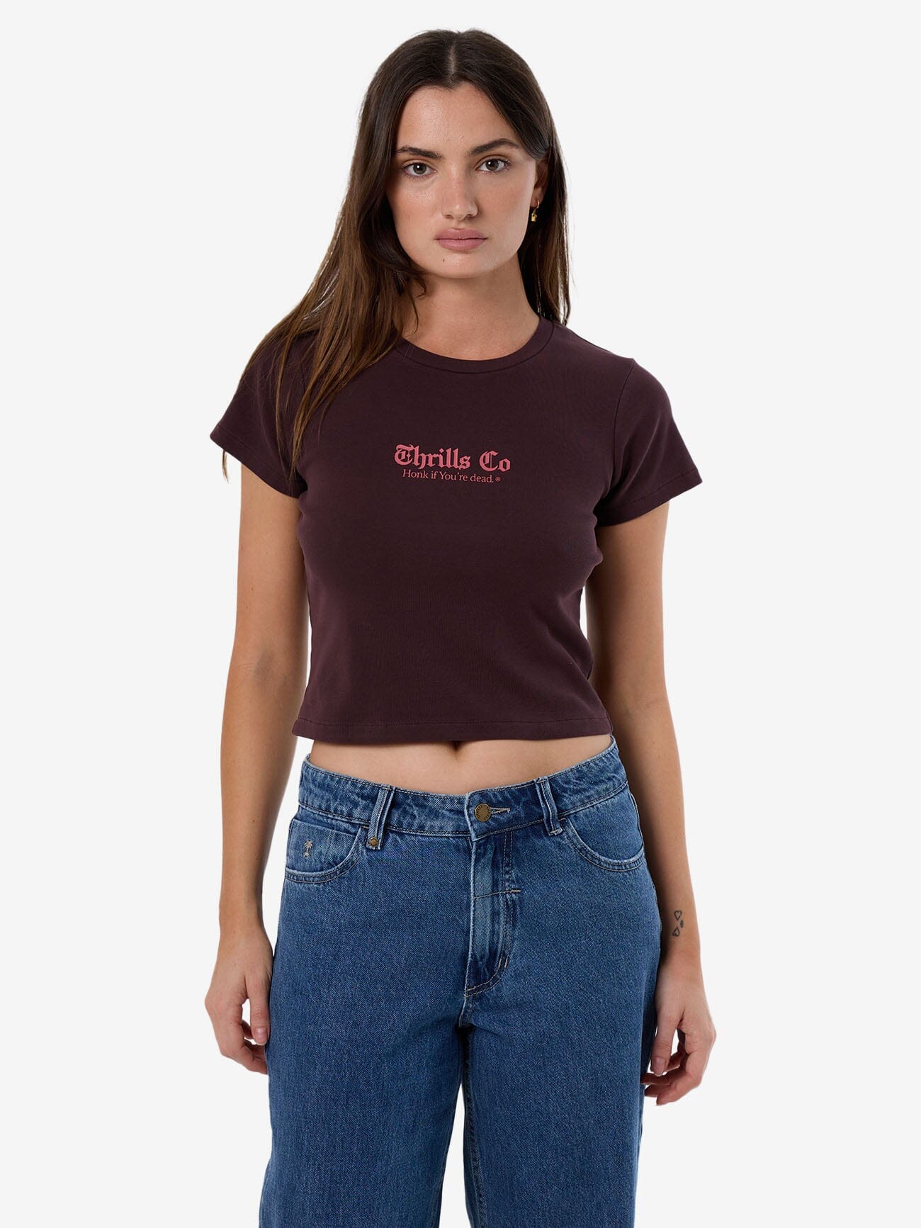 Female model wearing our Thrills Lighten Up Mini Tee or Baby Tee in Red standing against a plain studio background.