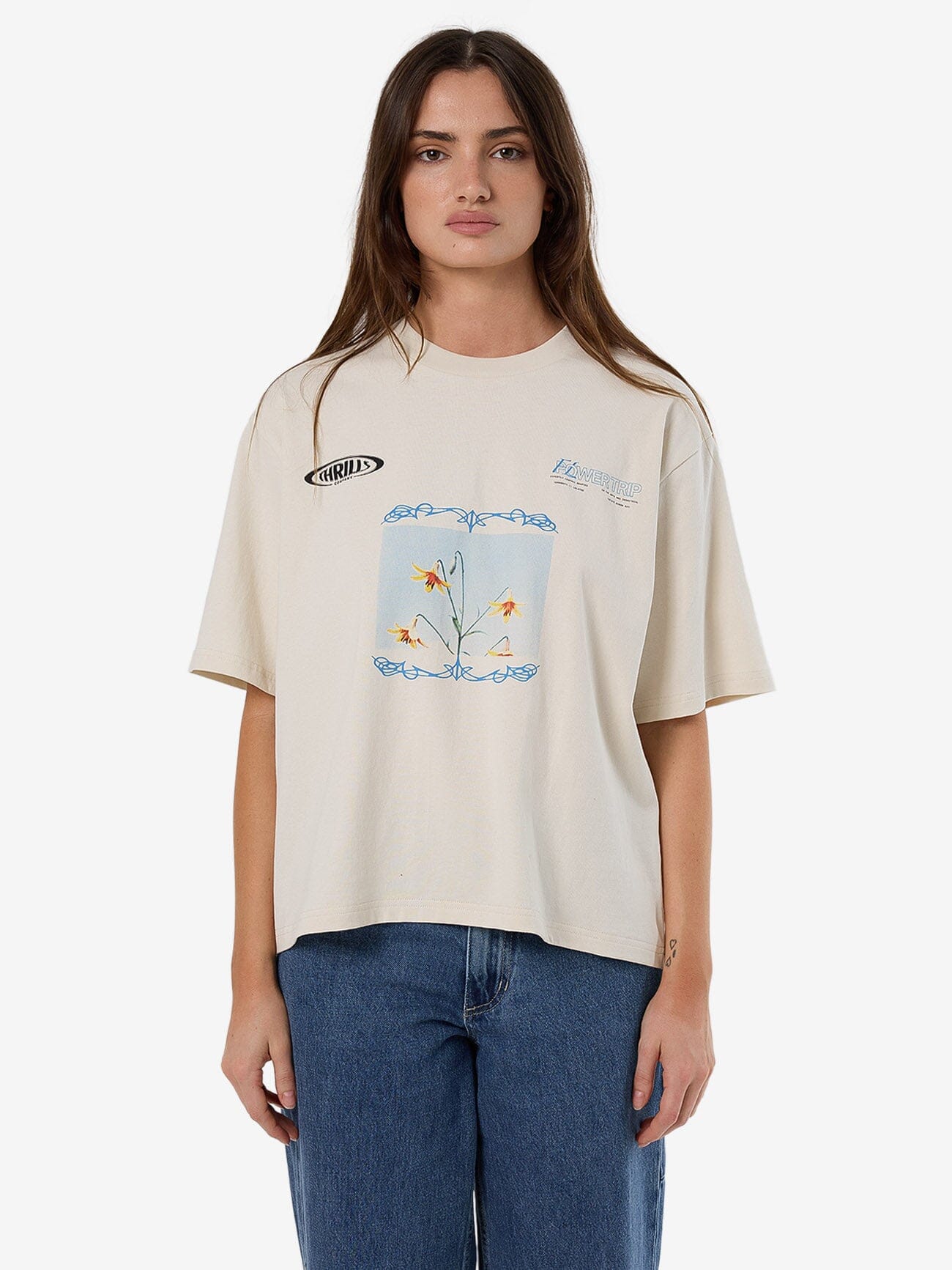 Female model wearing our Thrills Flower Trip Square Tee in White standing against a plain studio background.