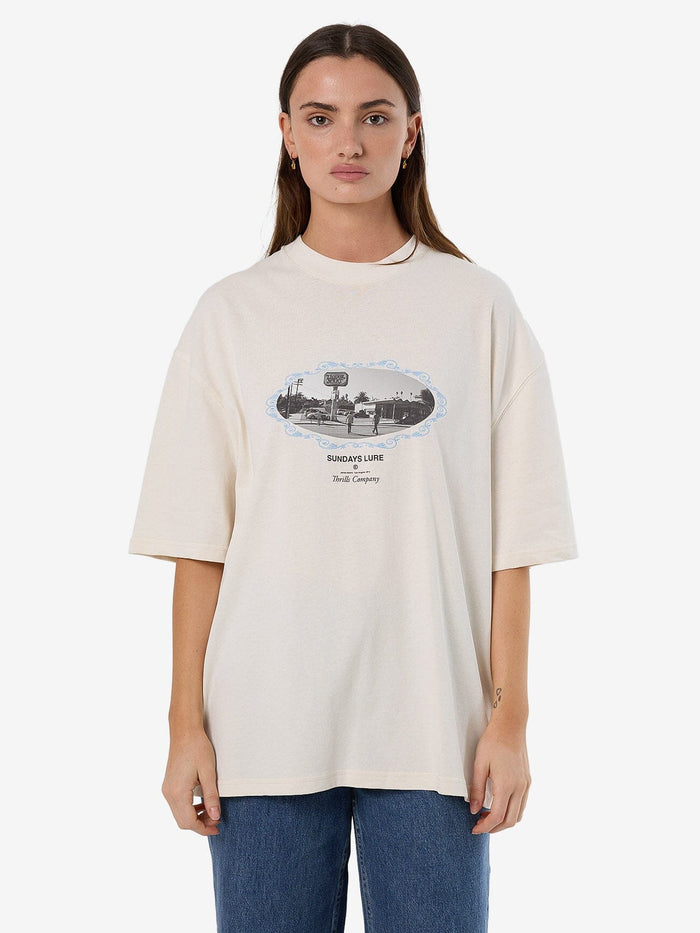 Female model wearing our Thrills Sundays Lure Oversized Tee in White standing against a plain studio background.