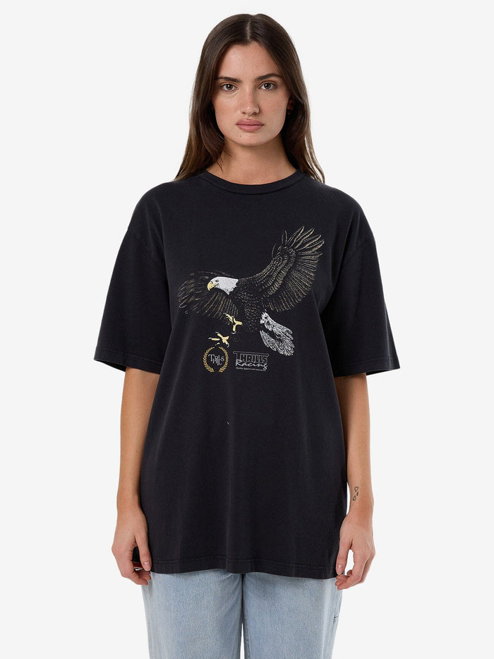 Female model wearing our Thrills Speed Tour Oversized Tee in Black standing against a plain studio background.