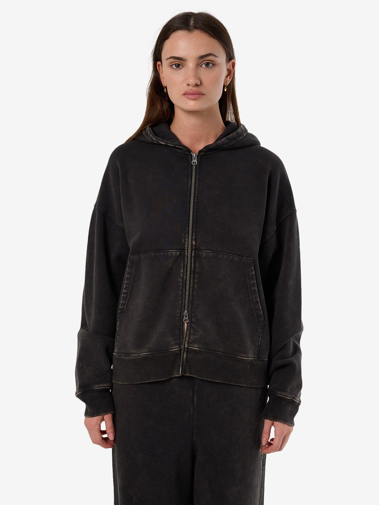 Female model wearing our Thrills Dissolve Zip Hood Fleece in Grey standing against a plain studio background.