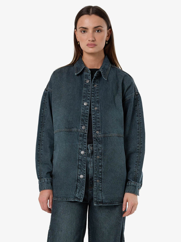 Female model wearing our Thrills Spencer Denim Overshirt in Blue standing against a plain studio background.