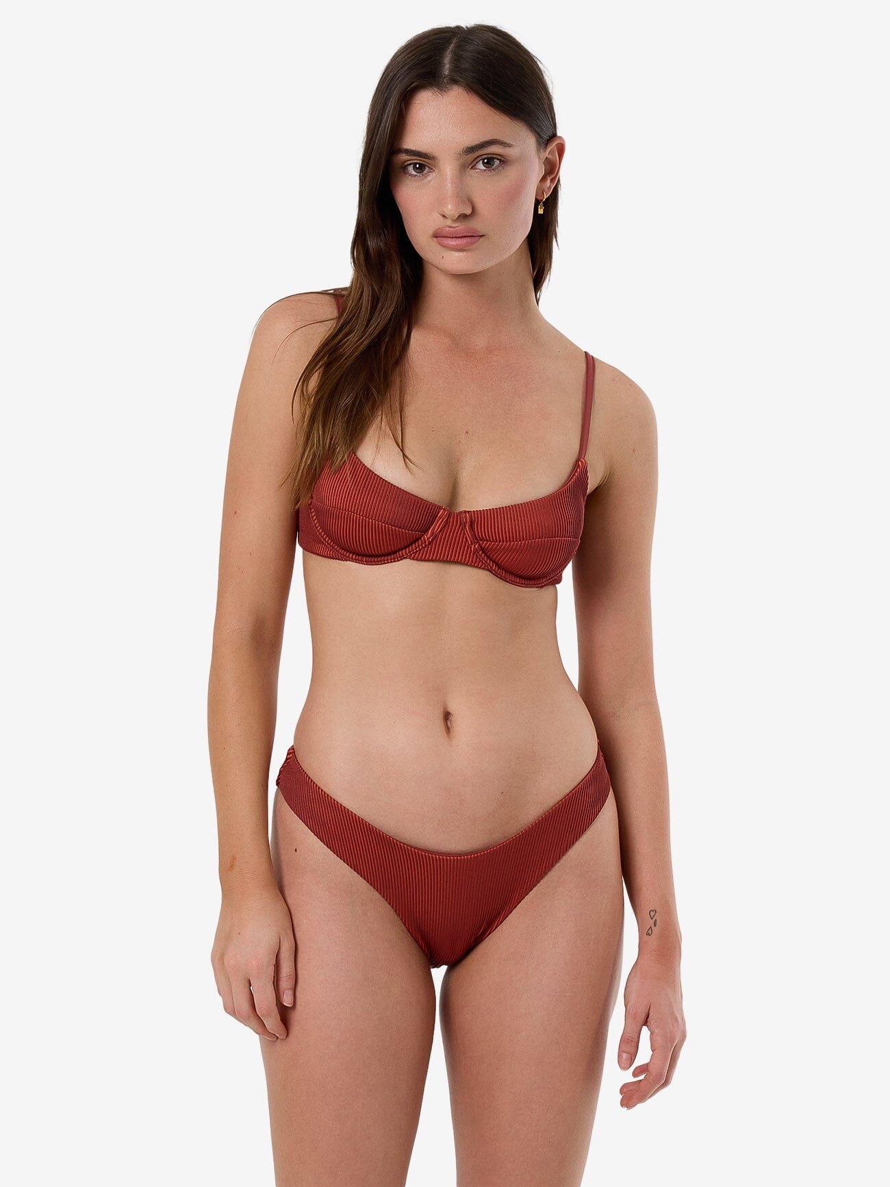 Female model wearing our Thrills Alba Rib Underwire Bikini Top in Orange standing against a plain studio background.