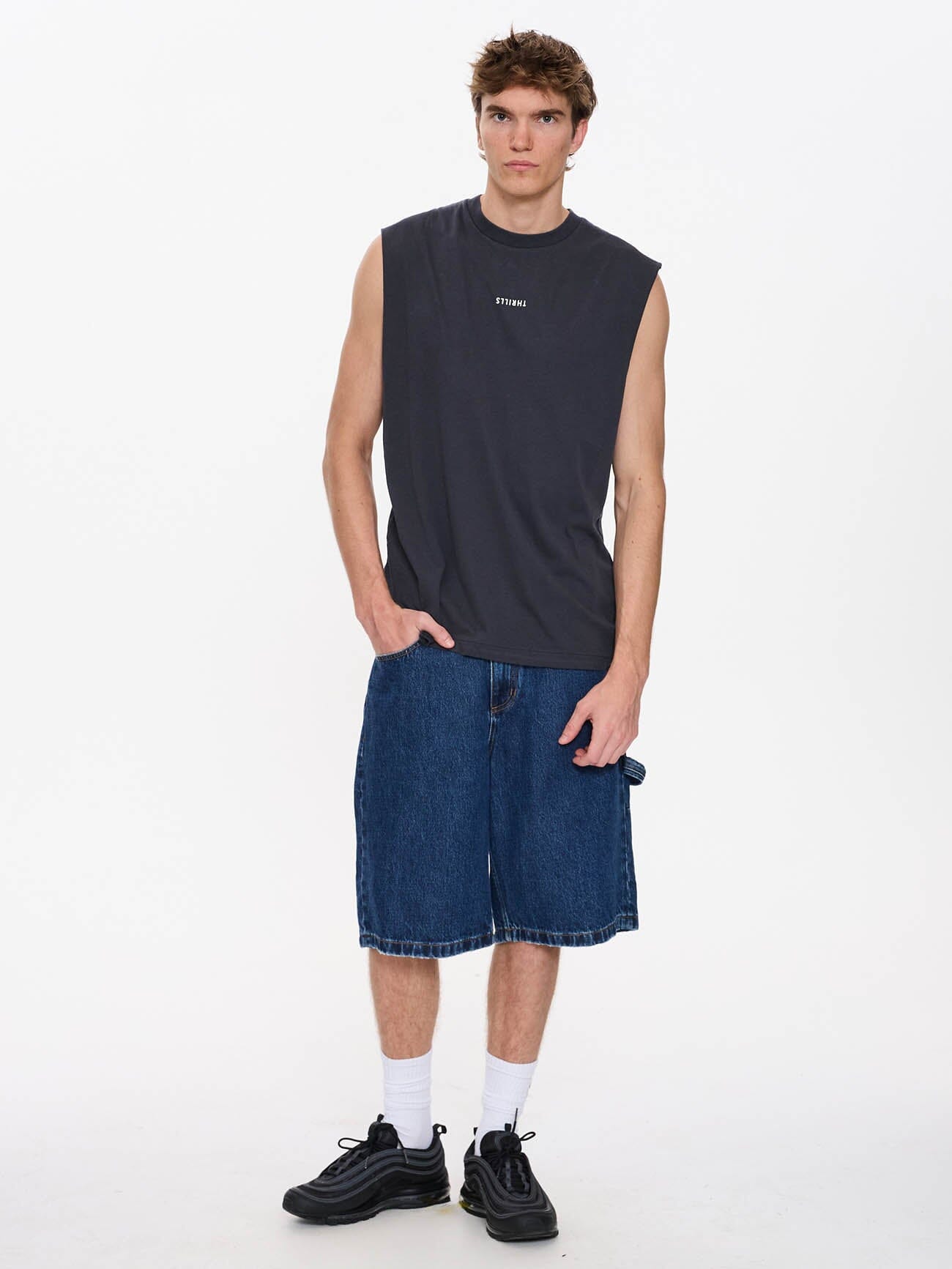 Male model wearing our Thrills Minimal Thrills Merch Fit Muscle Tee in Grey standing against a plain studio background.