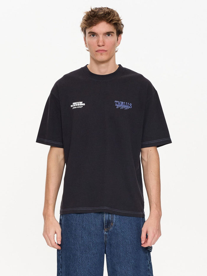 Male model wearing our Thrills Dispatch Box Fit Oversize Short Tee in Blue standing against a plain studio background.