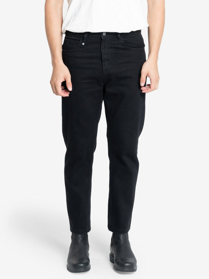 Male model wearing our Thrills Chopped Denim Jean in Black standing against a plain studio background.