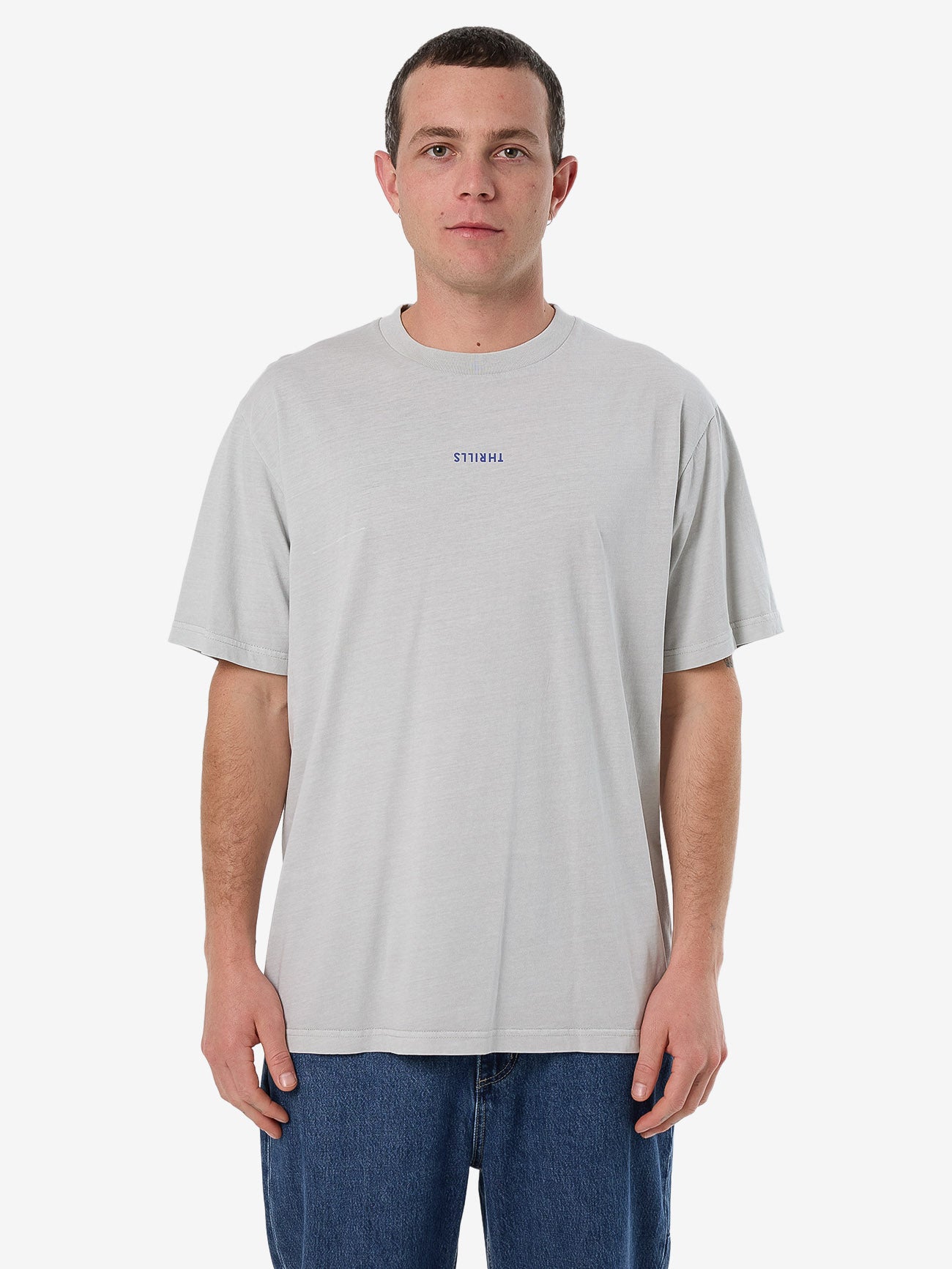 Male model wearing our Thrills Minimal Thrills Merch Fit Tee in White standing against a plain studio background.