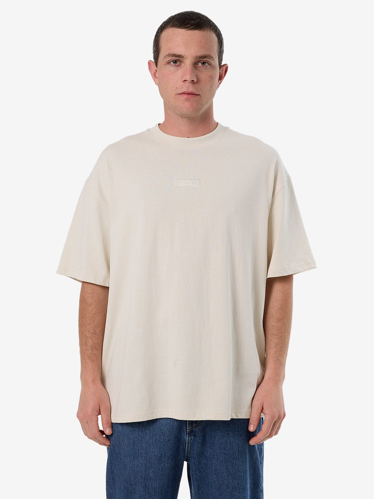 Male model wearing our Thrills Superior Thrills Box Fit Oversize Tee in White standing against a plain studio background.
