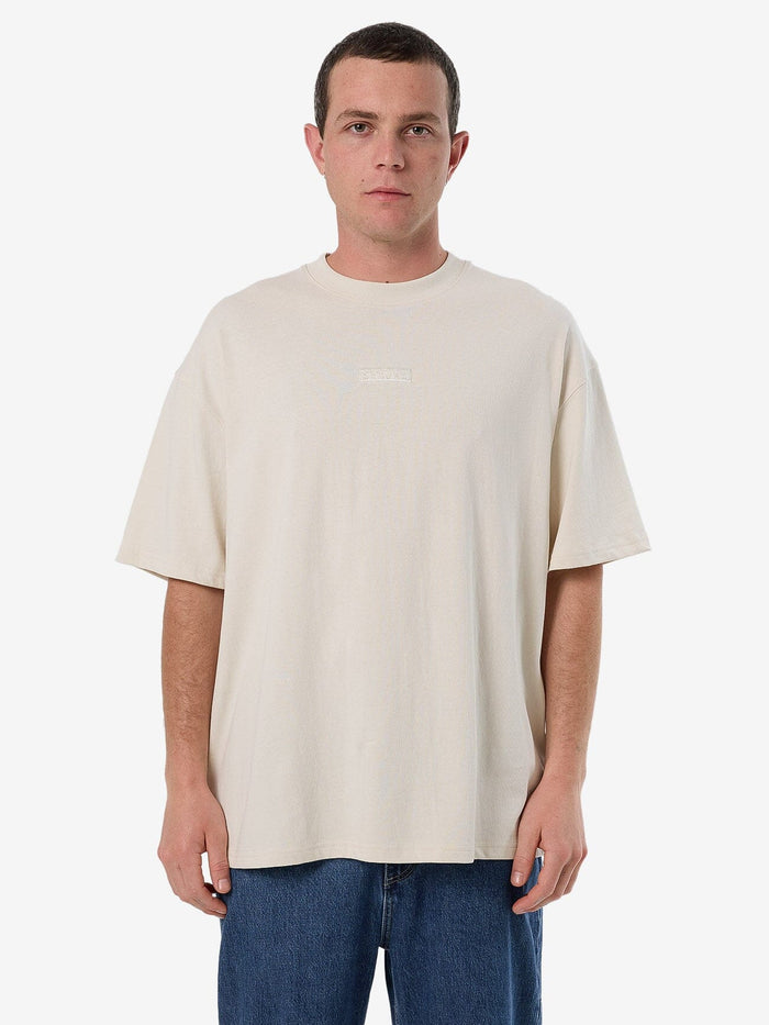 Male model wearing our Thrills Superior Thrills Box Fit Oversize Tee in White standing against a plain studio background.