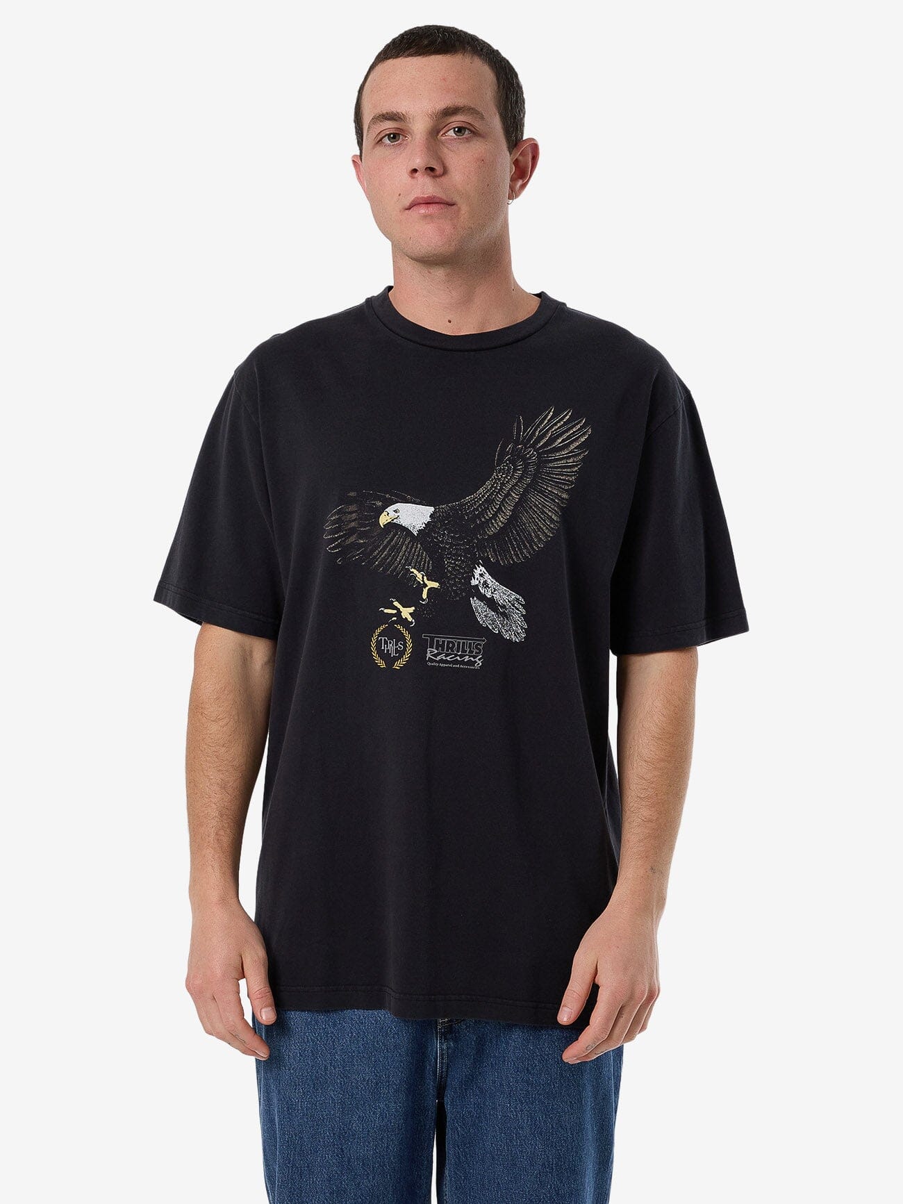 Male model wearing our Thrills Speed Tour Oversize Fit Tee in Black standing against a plain studio background.