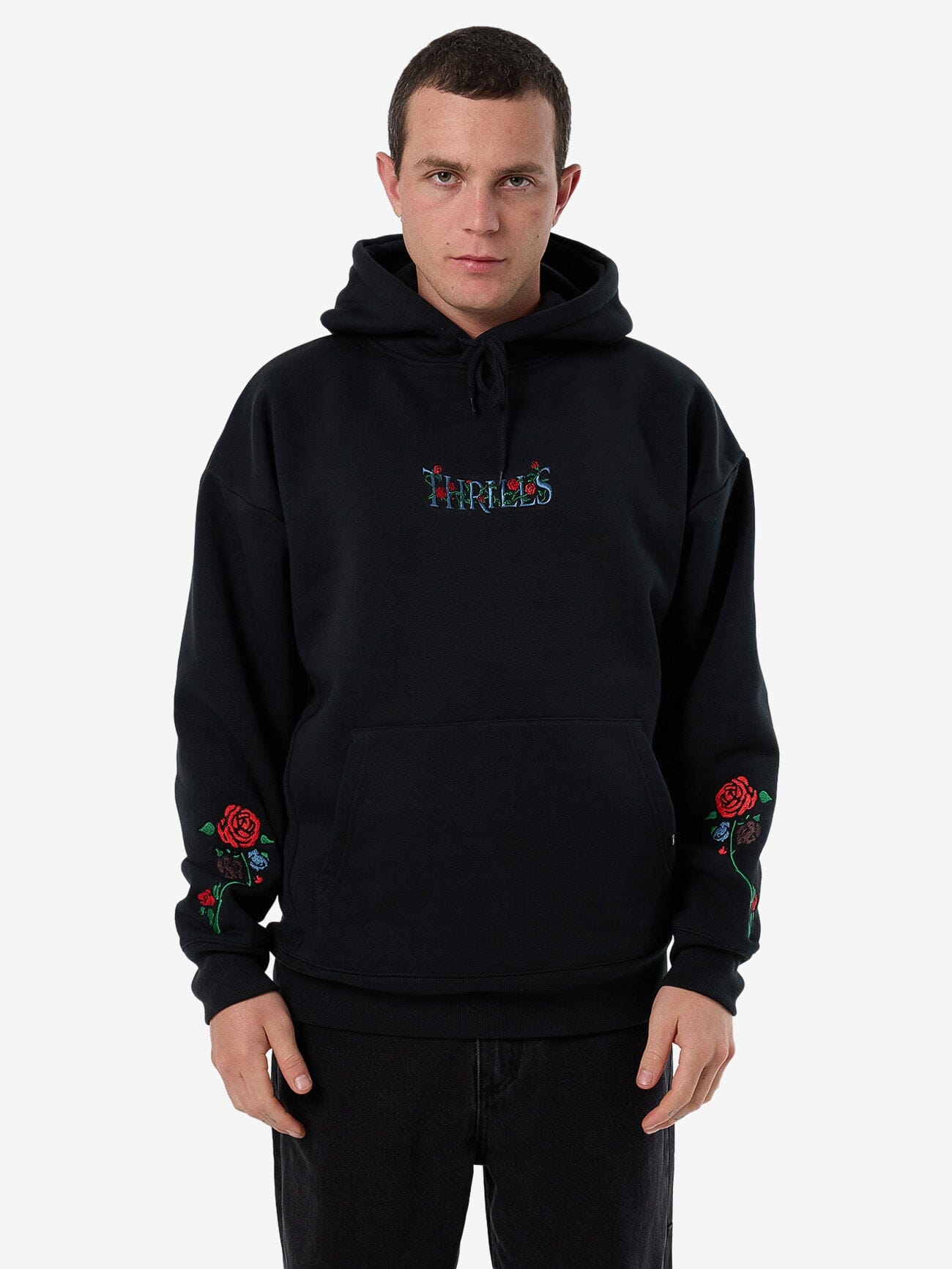 Male model wearing our Thrills Thorned Slouch Pull On Hood in Black standing against a plain studio background.