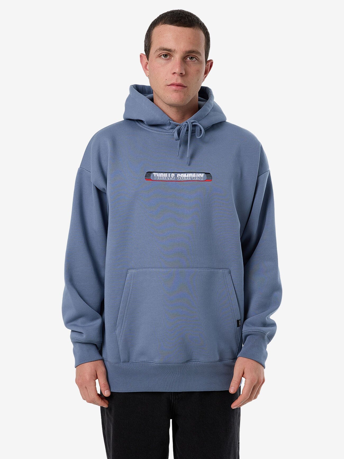 Male model wearing our Thrills Paid In Full Slouch Pull On Hood in Blue standing against a plain studio background.
