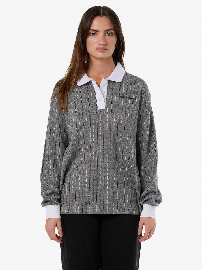 Female model wearing our Thrills  Limitations Stripe Rugby Long Sleeve Polo in Black standing against a plain studio background.