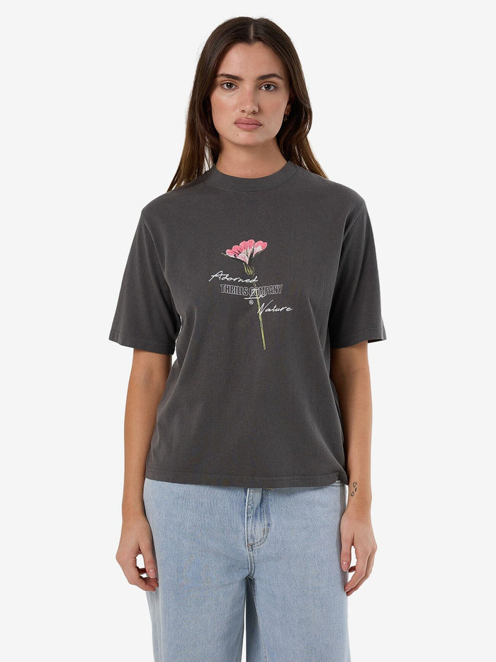 Female model wearing our Thrills  Adorned In Nature Square Tee in Black standing against a plain studio background.