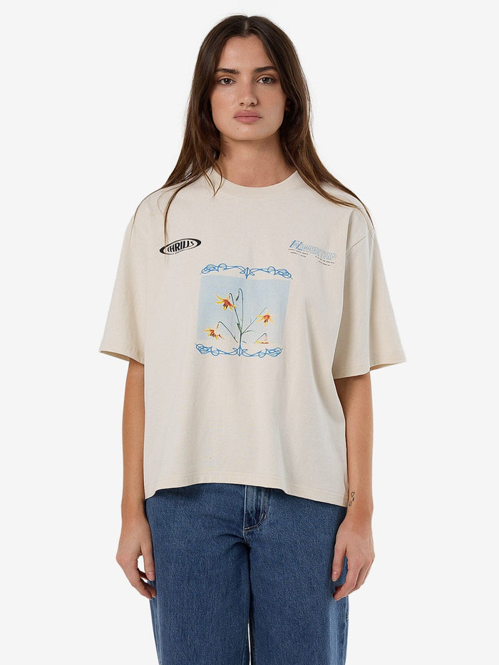 Female model wearing our Thrills Flower Trip Square Tee in White standing against a plain studio background.