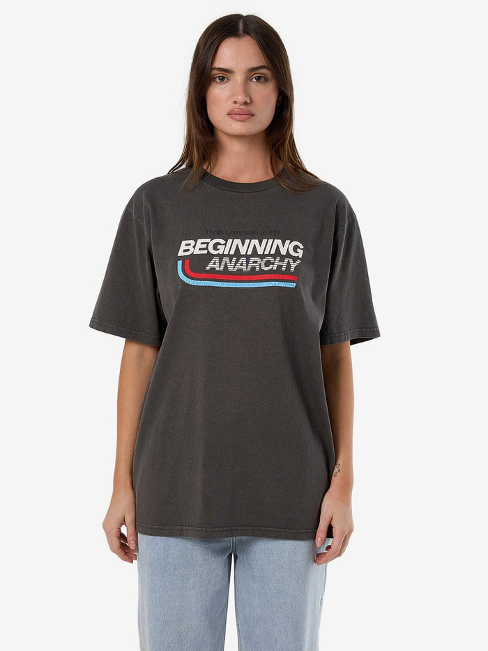 Female model wearing our Thrills Beginning Anarchy Merch Tee in Black standing against a plain studio background.