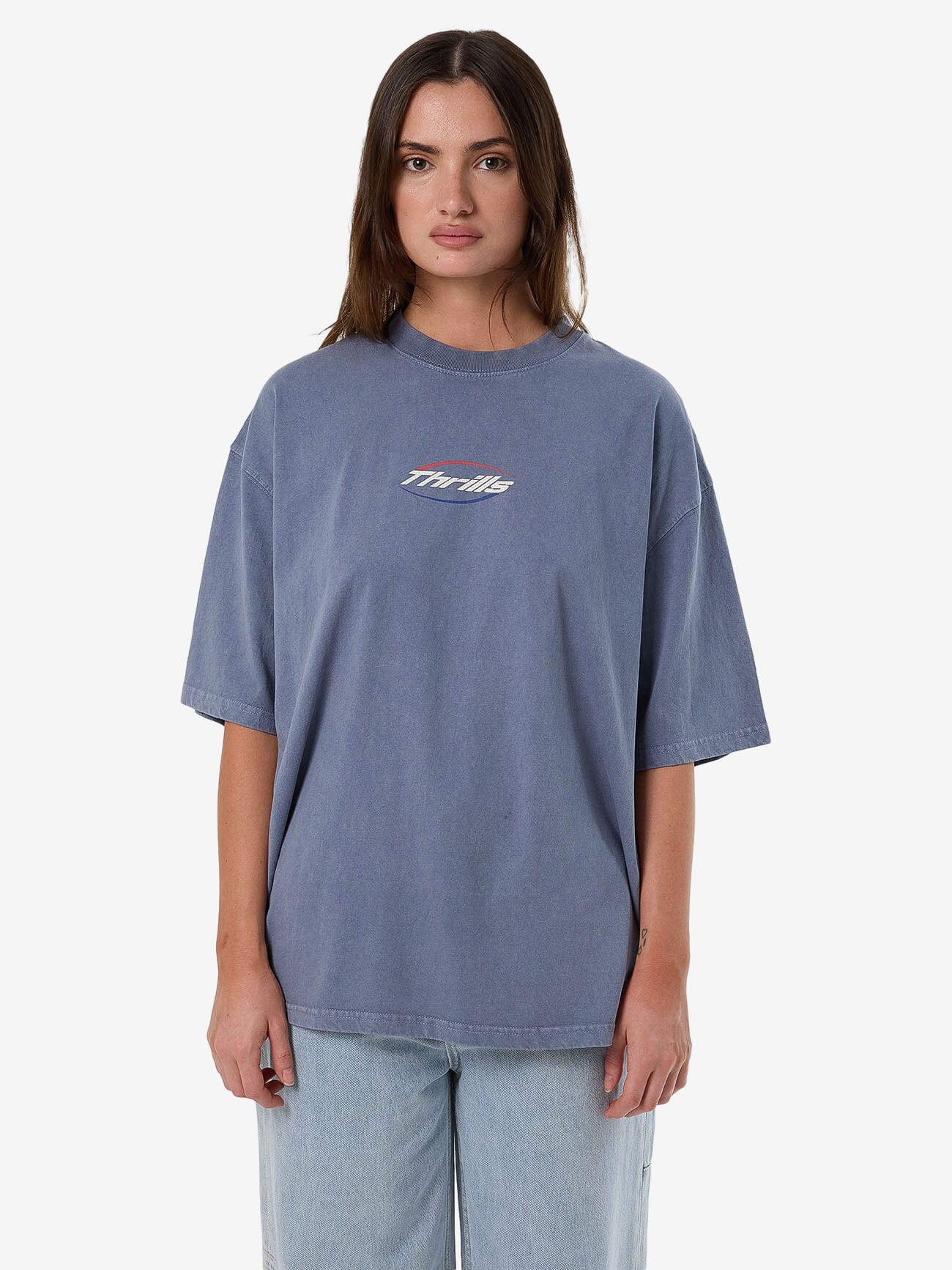 Female model wearing our Thrills Fortune Favours Oversized Tee in Blue standing against a plain studio background.