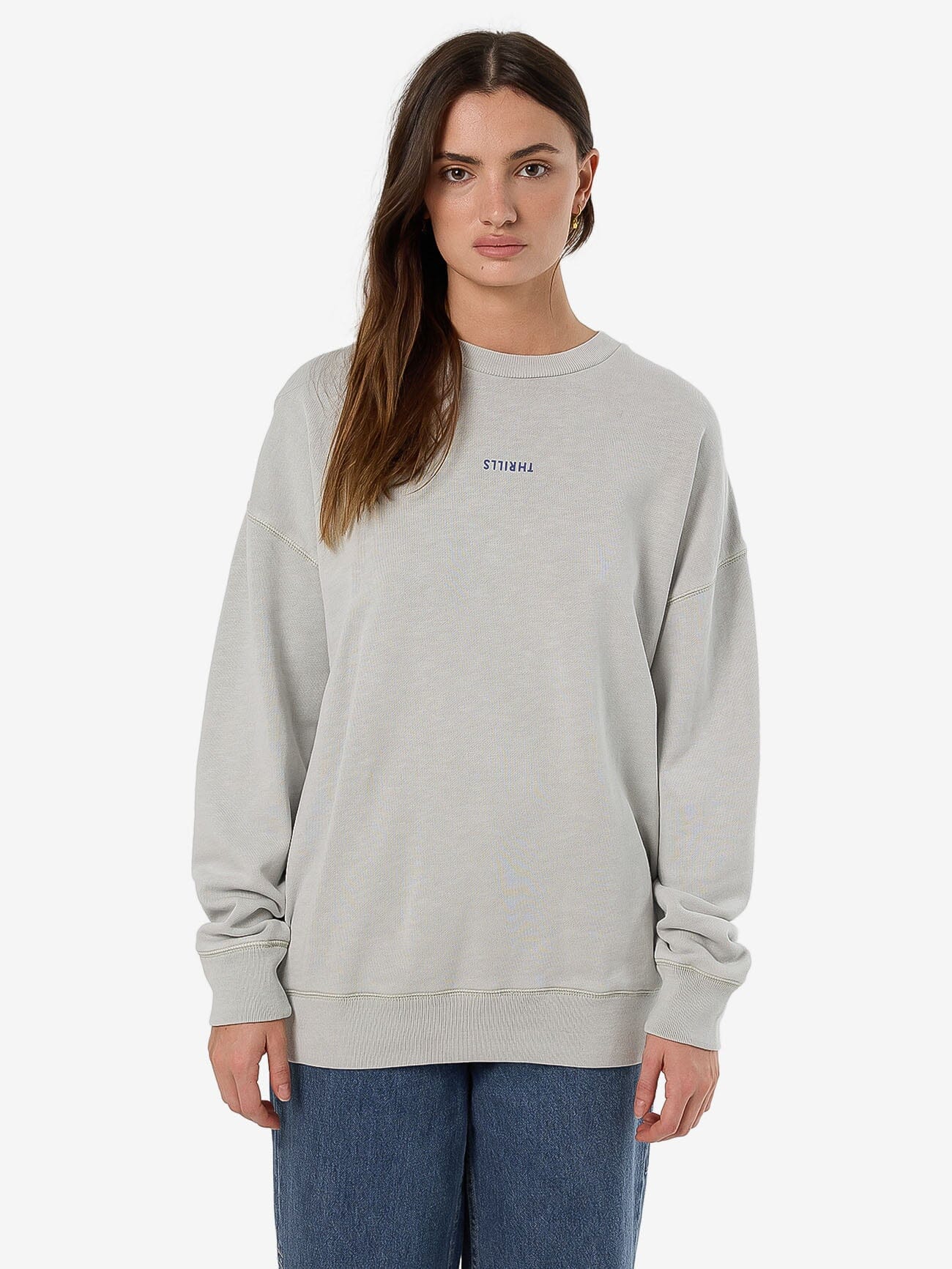 Female model wearing our Thrills Minimal Thrills Slouch Crew in White standing against a plain studio background.