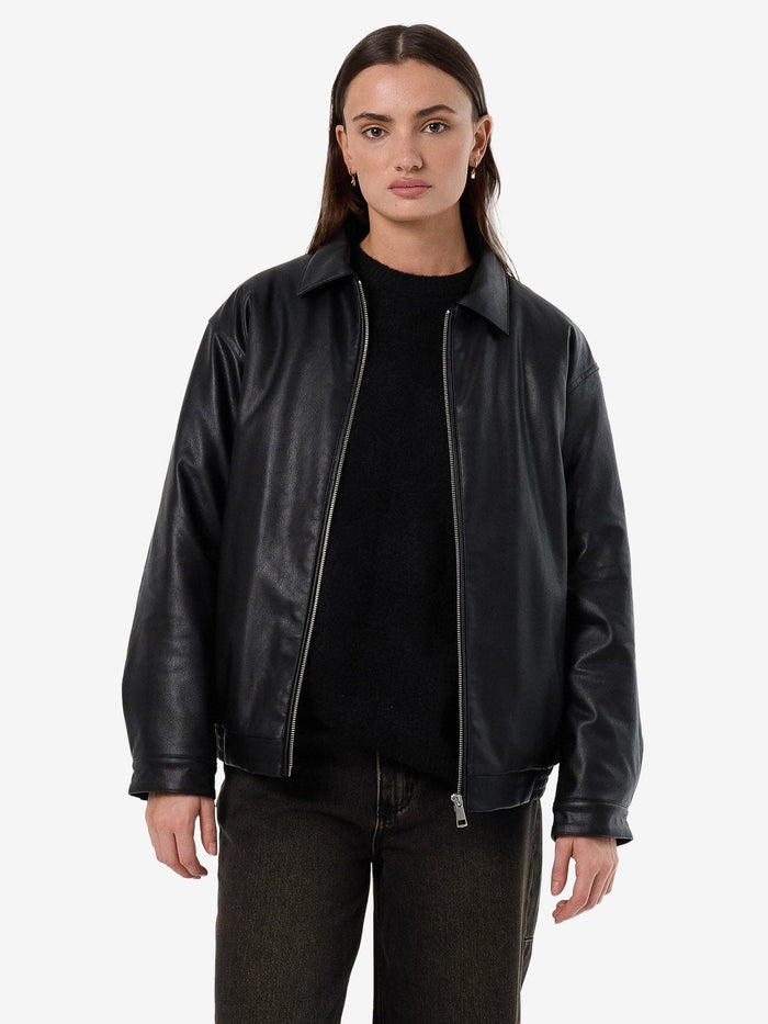 Female model wearing our Thrills Miles Leather Jacket in Black standing against a plain studio background.