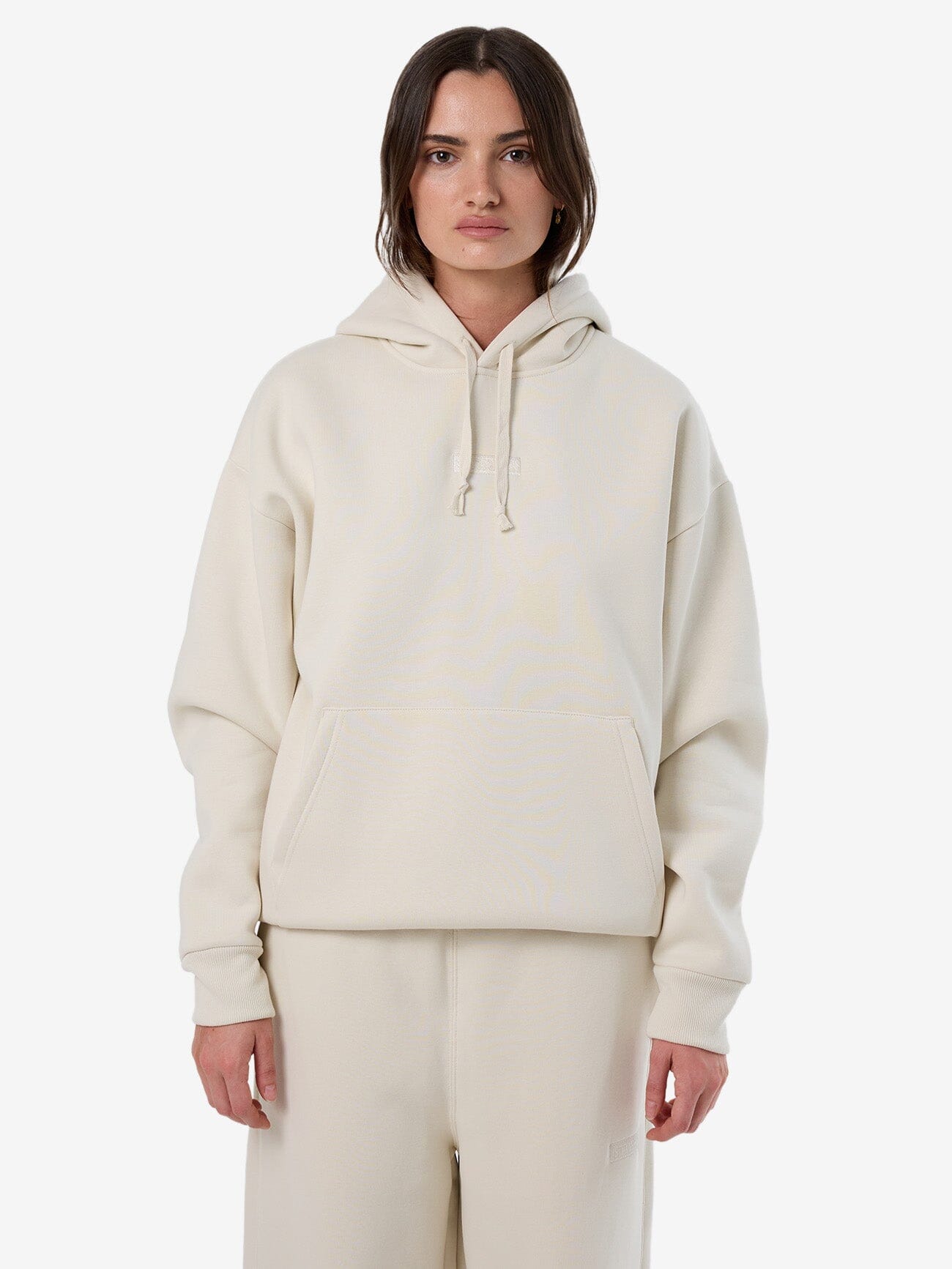 Female model wearing our Thrills Superior Slouch Hood in White standing against a plain studio background.
