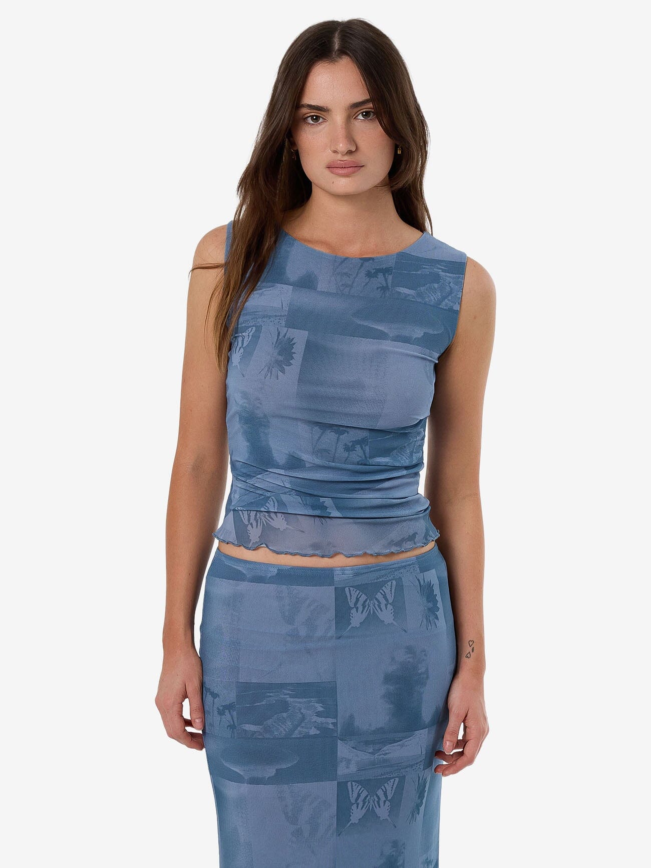 Female model wearing our Thrills Eclipse Haze Mesh Tank in Blue standing against a plain studio background.